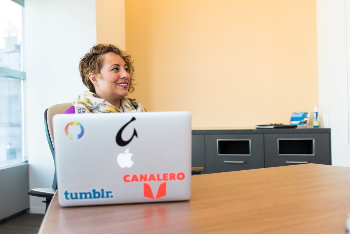 A woman sits in the office at a computer covered with colorful stickers