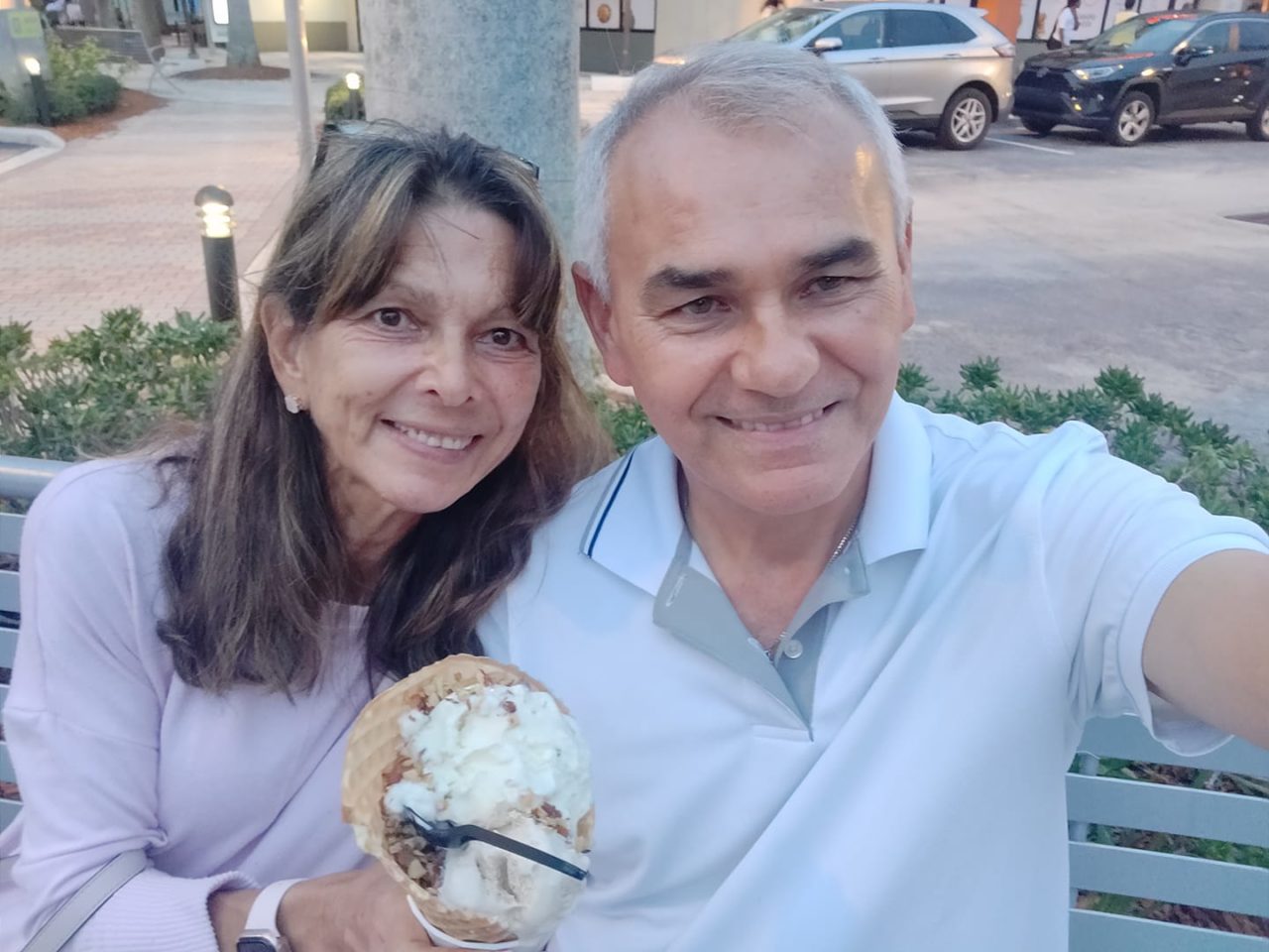 Two people take a selfie over ice cream. One is a woman with dark hair. The other a gentleman with short gray hair.