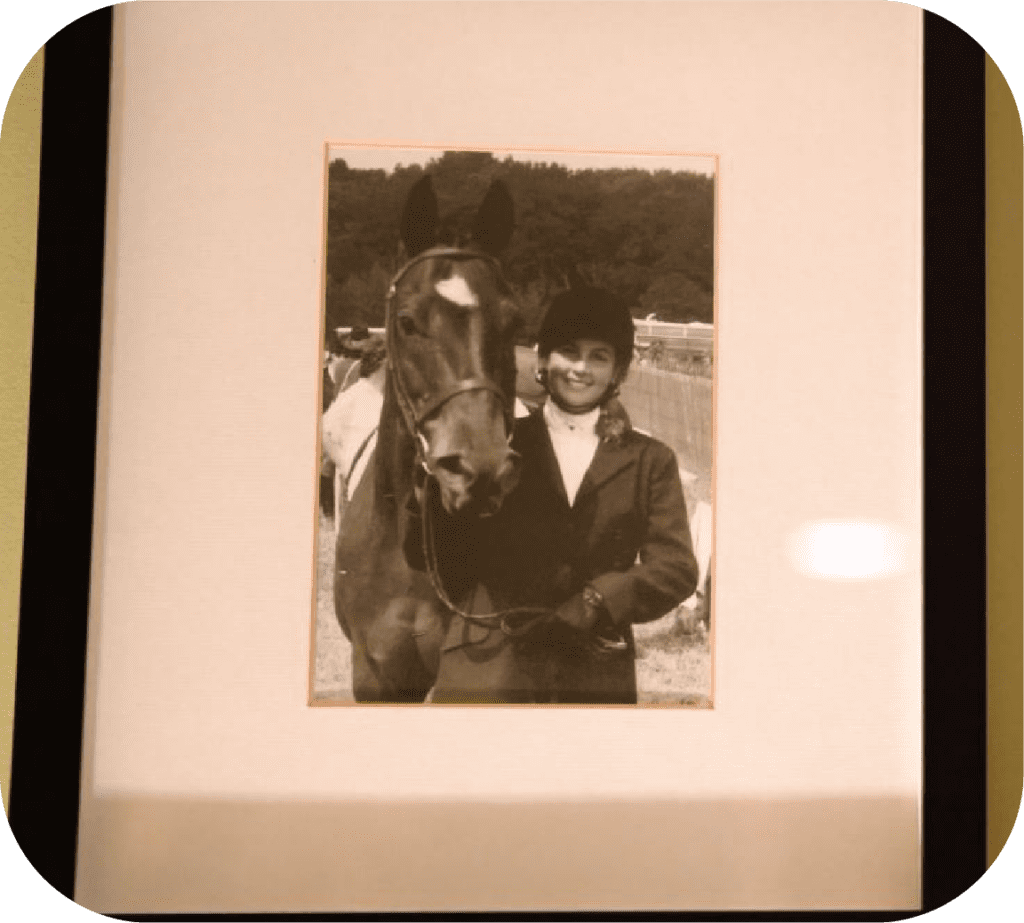 A framed photo in black and white of Jennifer with a horse. She is smiling into the camera. It is before the accident.