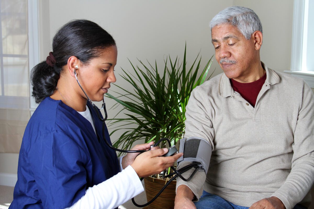 A home health care worker takes the blood pressure of a person aging at home.
